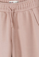 Close-up of pink wide leg joggers with elasticated waistband and side pockets, showcasing soft fabric texture and design details.