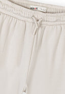 Close-up of off white wide leg joggers with elasticated waist and drawstring detail in kids fashion design