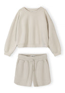 Beige women’s sweatshirt and shorts set featuring crew neck, elasticated waist, and a comfortable relaxed fit design.