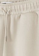 Close-up of beige shorts with elasticated waist and drawstring showcasing soft fabric and refined design details