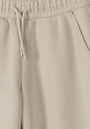 Close-up of beige wide leg joggers with elasticated waistband and drawstring showcasing soft breathable fabric design.