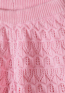 Close-up of soft pink crochet fabric showcasing detailed heart and geometric design pattern on kidswear.