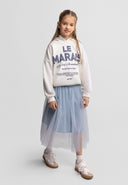Young girl wearing a grey pleated tulle maxi skirt paired with casual sweatshirt and sneakers, showcasing a stylish kids fashion look.