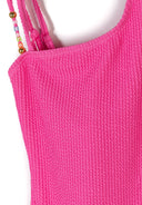 Close-up of bright pink textured swimsuit fabric with delicate double straps featuring bead details