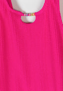 Close-up of bright pink textured fabric girls swimsuit with colorful bead detail spelling smile at scoop neck design
