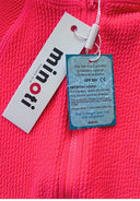 Close-up of pink textured swimsuit fabric with front zipper and attached care and protection tags