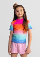Girl wearing a colorful ombre rash top in pink, orange, blue tones paired with light pink shorts showcasing kids fashion design