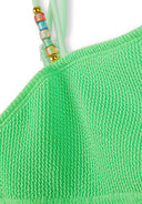 Close-up of textured bright green fabric with colorful beads on adjustable straps of girls swimwear design.