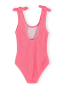 Pink textured girls swimsuit with sleeveless design and bow-knot shoulder straps, featuring a stylish low back cut.