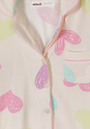 Close-up of soft fabric with pastel pink, green, and purple heart design and button-up detail on kids sleepwear
