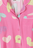 Soft pink kids pajama top with colorful heart patterns and white piping detail on collar and pocket