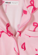 Close-up of soft pink fabric with a vibrant bow print design on a girls' short sleeve pajama set neckline and pocket.