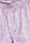 Close-up of lilac satin fabric with white heart print and elastic waistband detail in kids fashion design.
