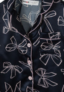 Navy satin fabric with a unique bow print design and pink piping along buttoned front and pocket edge