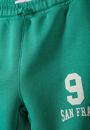 Green joggers featuring an elasticated waistband, side pockets, and printed number detail. Boys sweatshirt and joggers set half zip green 1-8y.